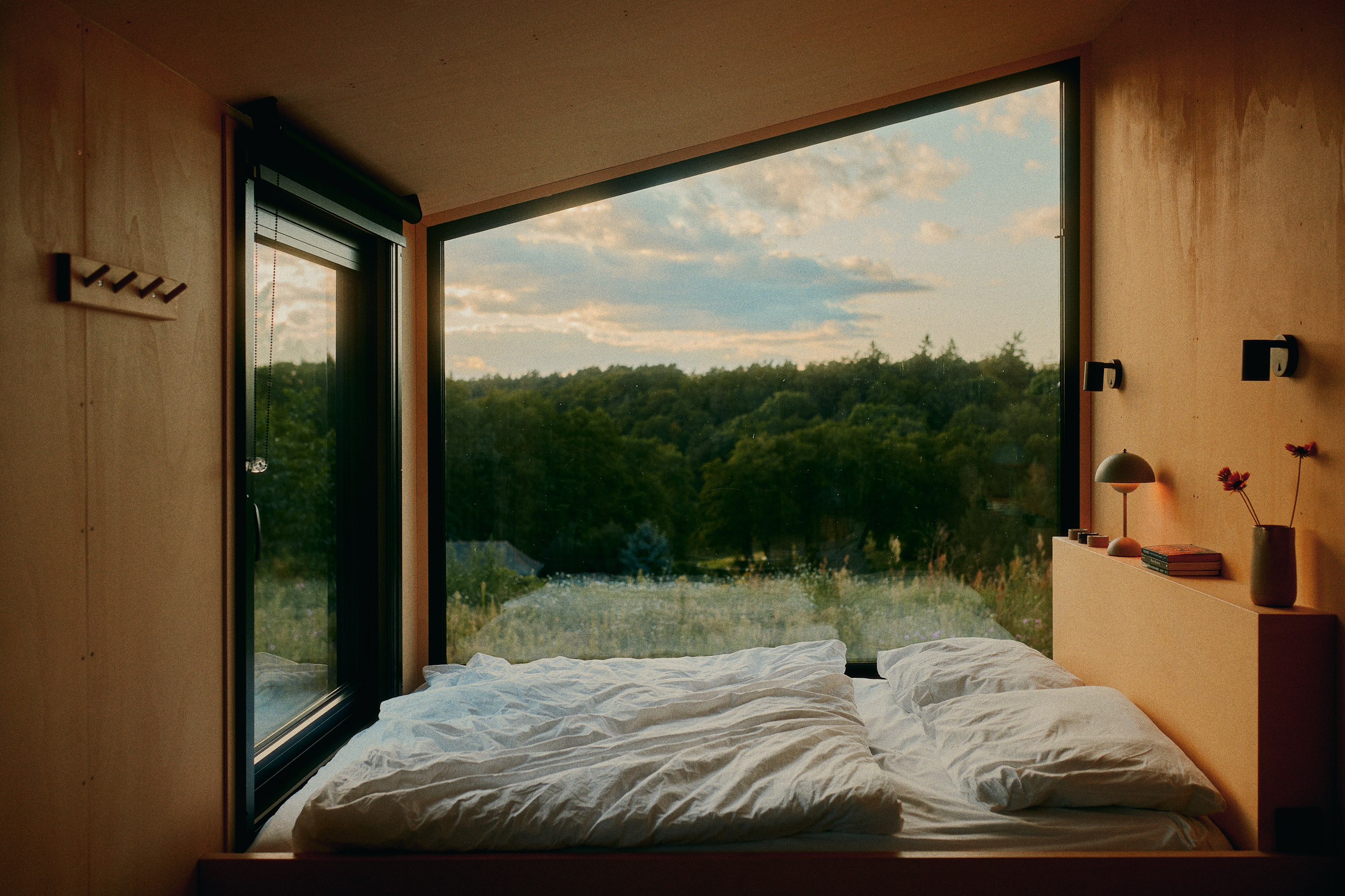 Modern eingerichteter Wohn-Schlafbereich einer Cabin in der Lodge am See von Raus mit Kaminofen, natürlichem Licht und warmem Holzambiente – Interior Fotografie von David Altrath.