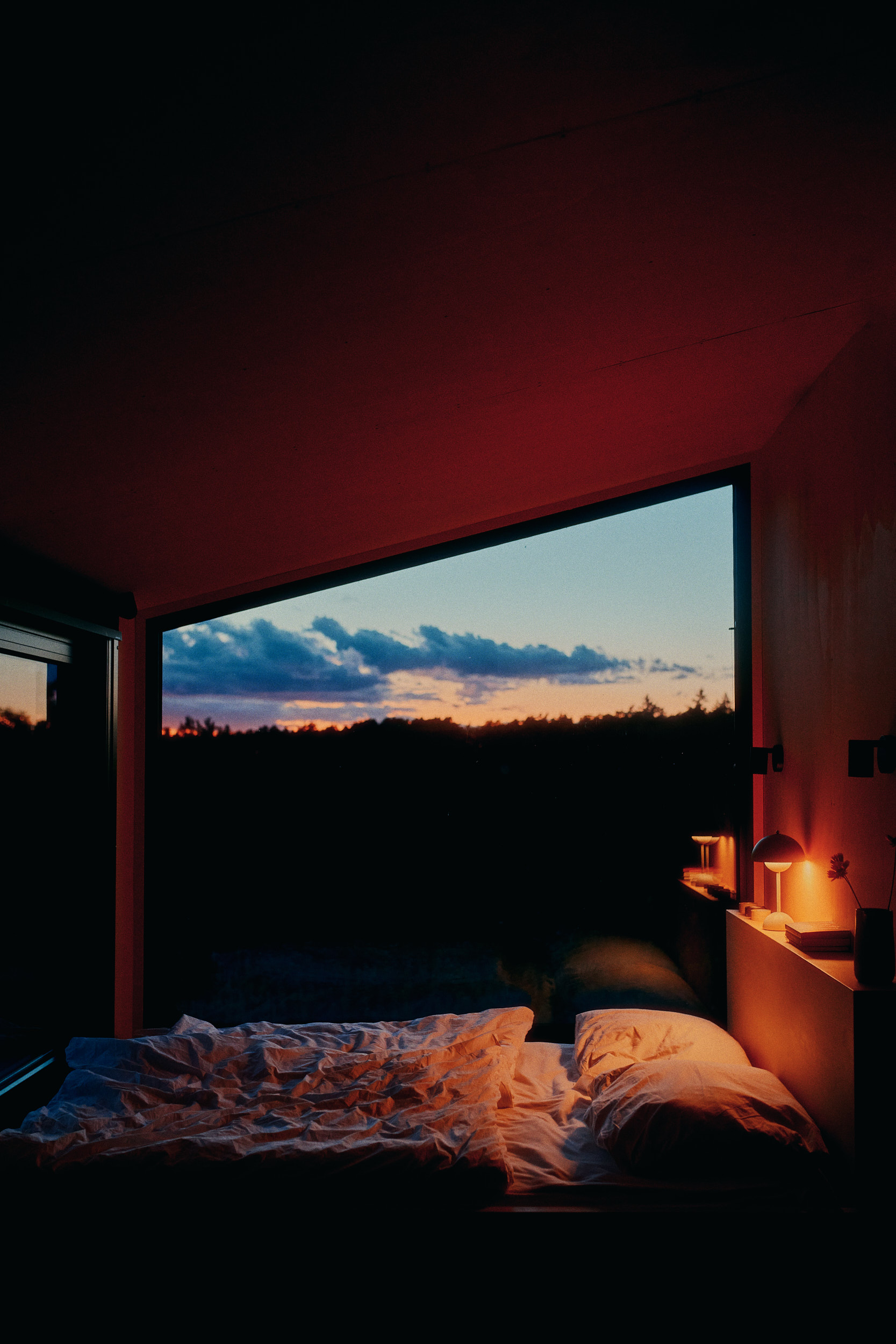 Interior shot by David Altrath: fireplace, wood cladding, and panoramic windows inside a Raus Lodge cabin in Brandenburg.
