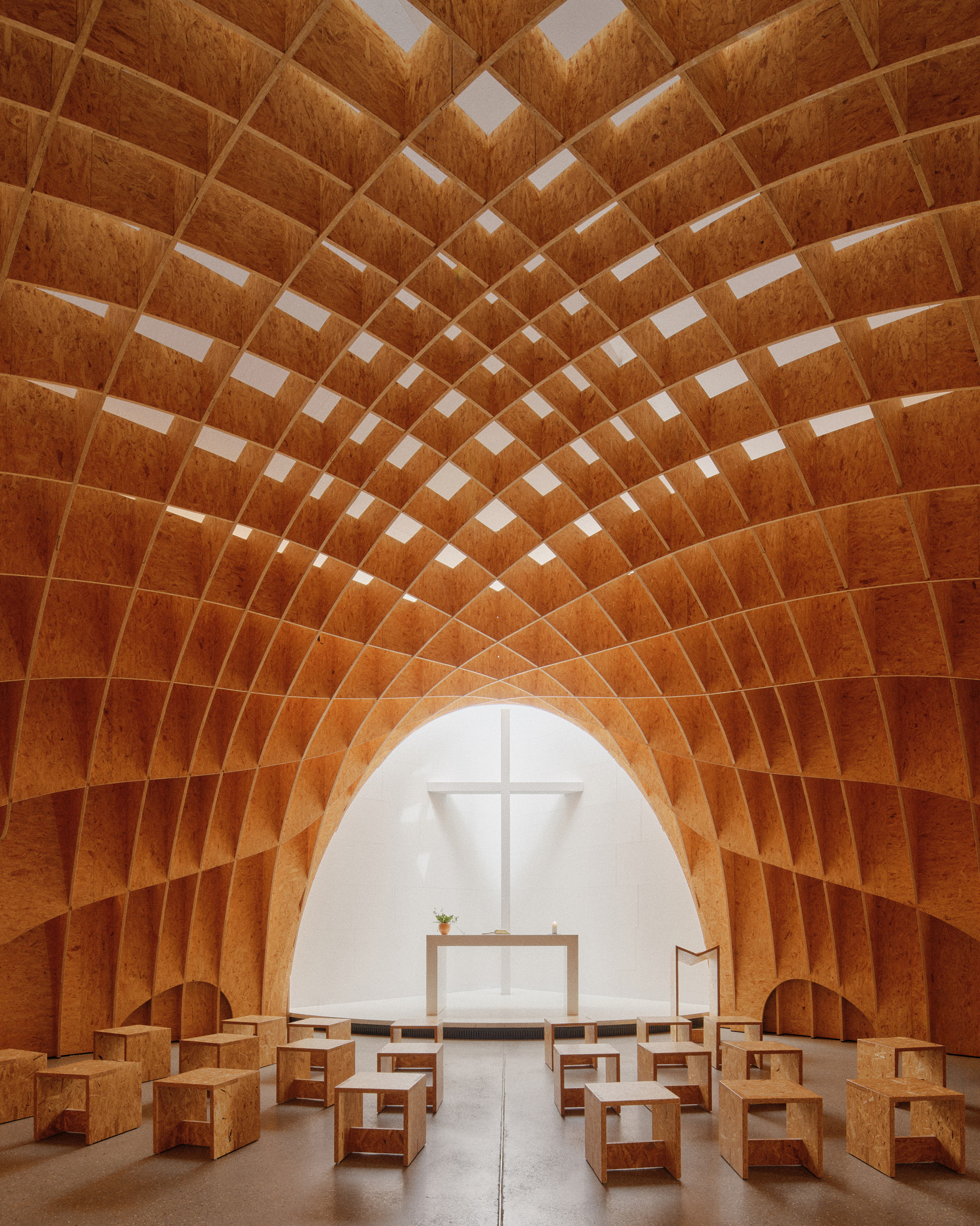Interior photography of Autobahnkirche Siegerland with a wide view of the warm timber interior, wooden vaulted structure and altar, captured by Hamburg architectural photographer David Altrath.